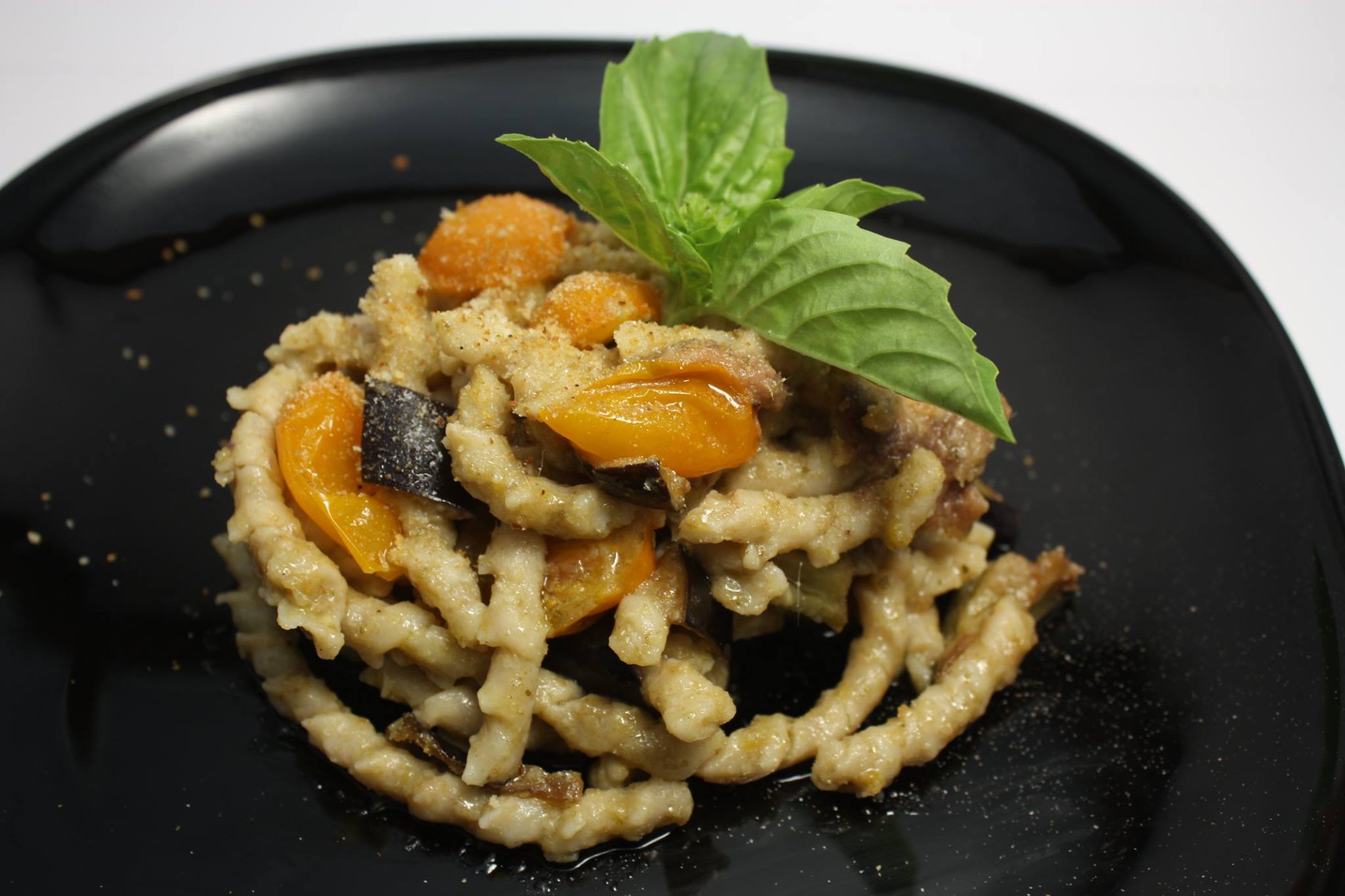 Busiate trapanesi di farina di tumminia, crema di capperi di Salina, filetti di acciughe di Sciacca, melanzane, pomodorini gialli e pan grattato