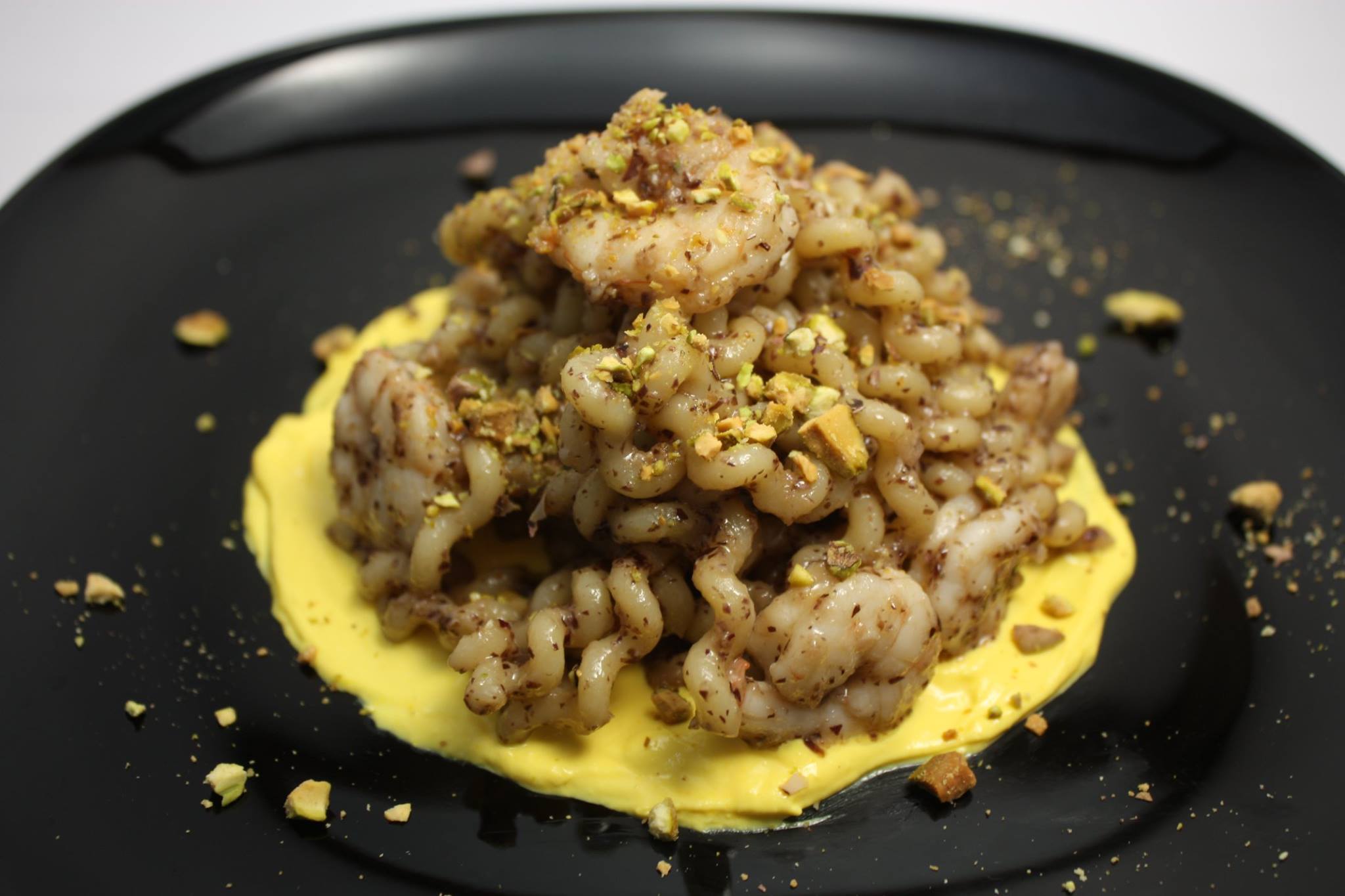Fusilli lunghi con pesto di radicchio, gamberi e pistacchi su crema di ricotta colorata allo zafferano
