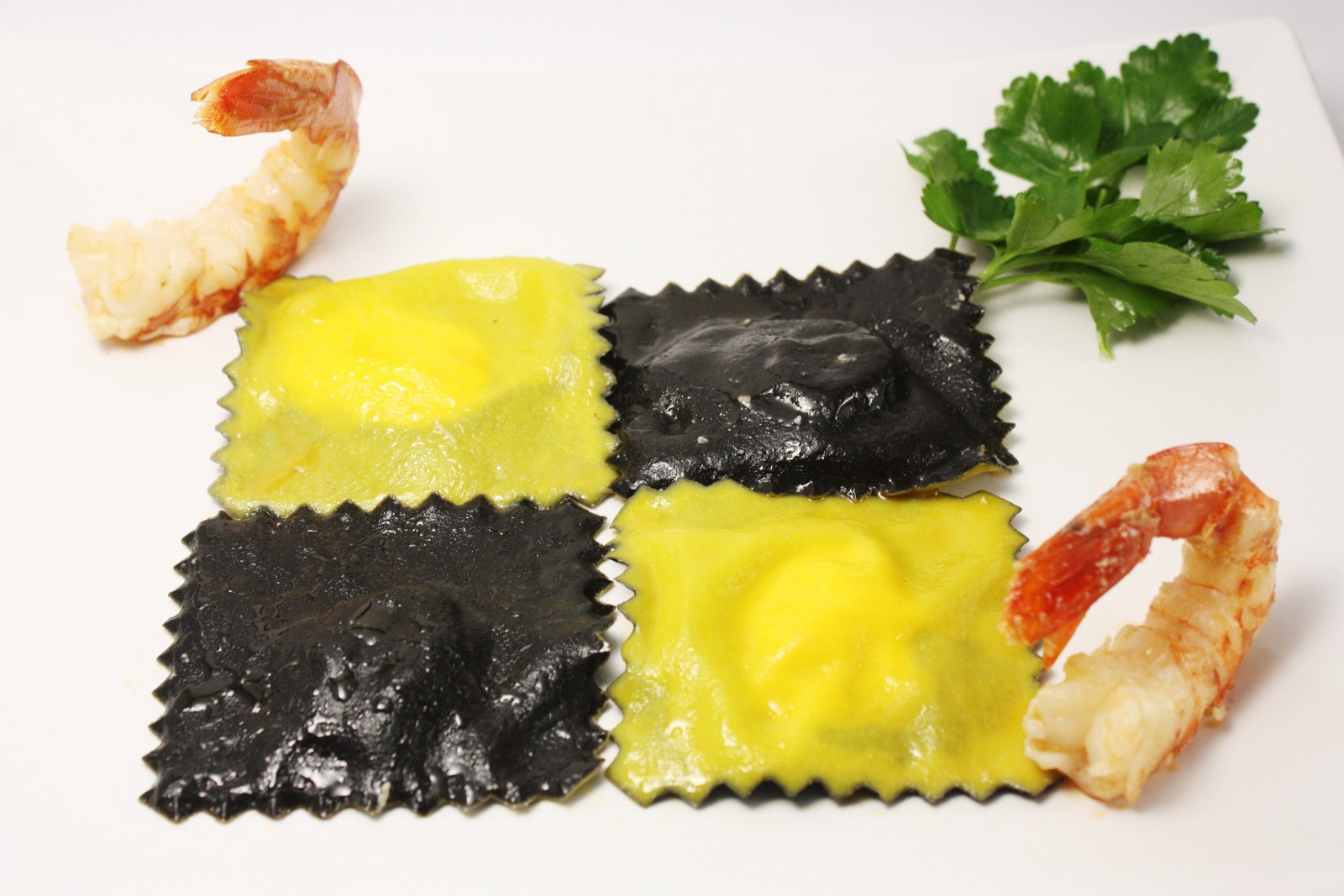 Ravioli bicolore allo zafferano e al nero di seppia con gamberi
