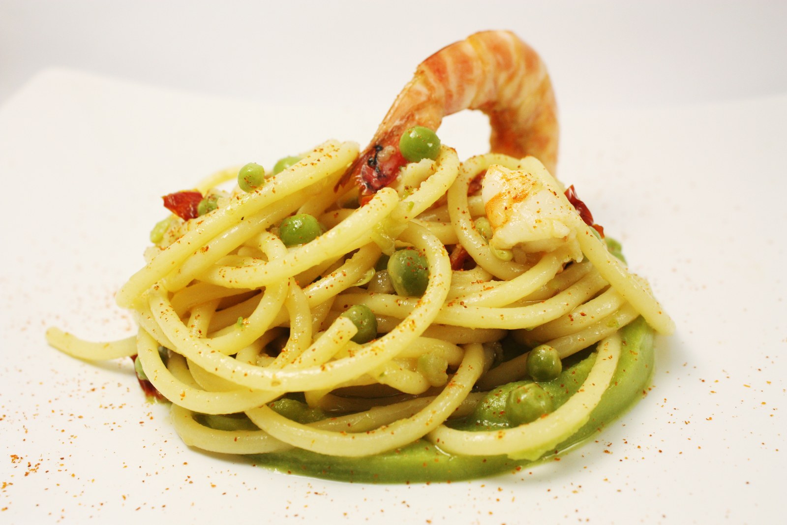 Bucatini lardiati con piselli freschi, pomodori secchi e mazzancolle