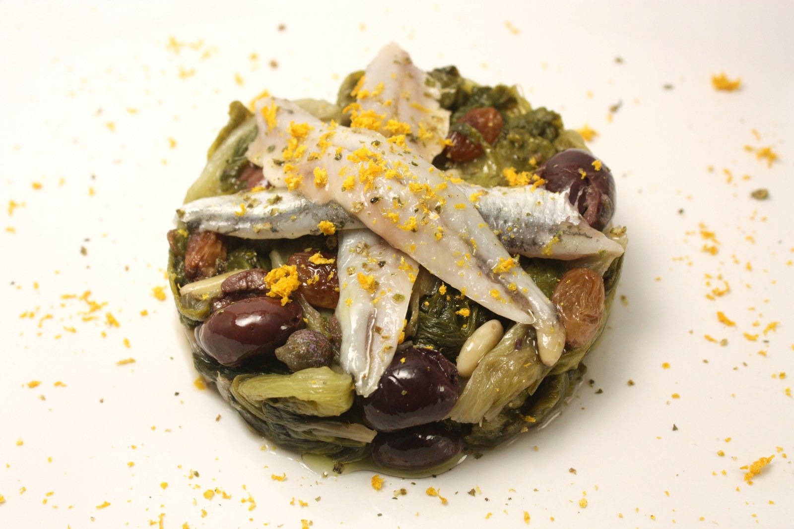 Alici marinate all&rsquo;arancia su scarole con olive nere, capperi, pinoli e uva passa